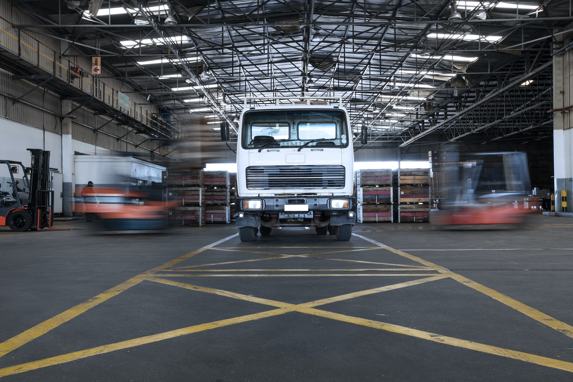 Parked truck in warehouse and moving forklifts